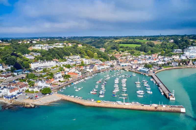 Aerial view of St Aubin harbour in Jersey, with boats moored in turquoise water