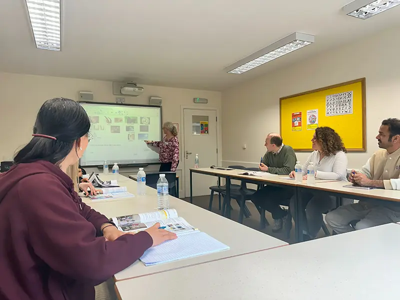 Adult students in class with their teacher and an interactive screen