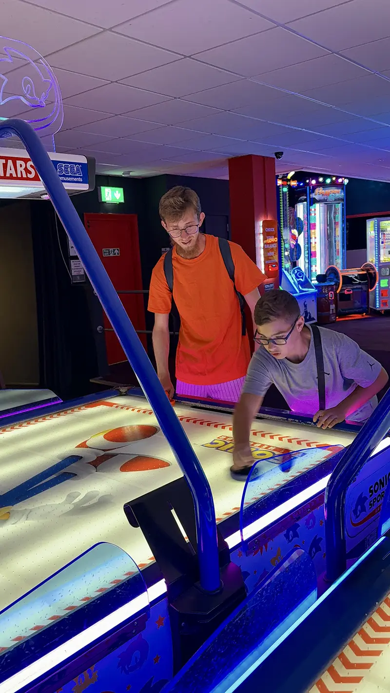 Student playing air hockey with activity leader
