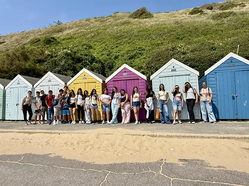 Students in front of beach huts on a school excursion