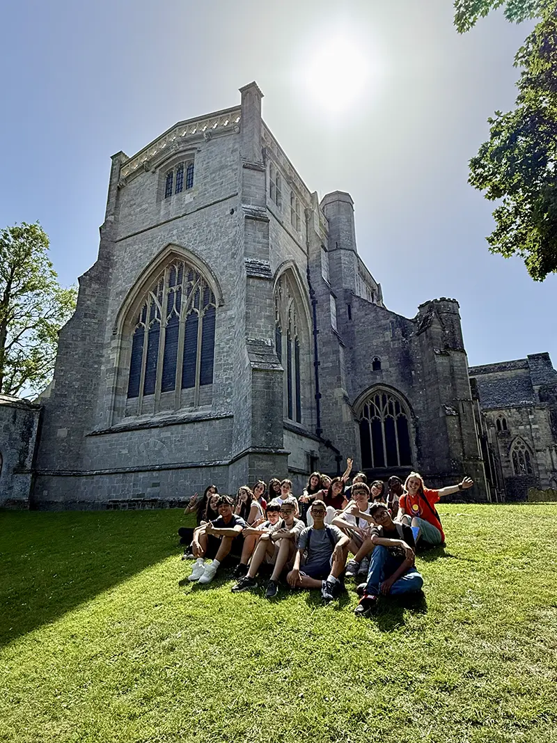 Students sat outside christchurch priory on a school excursion