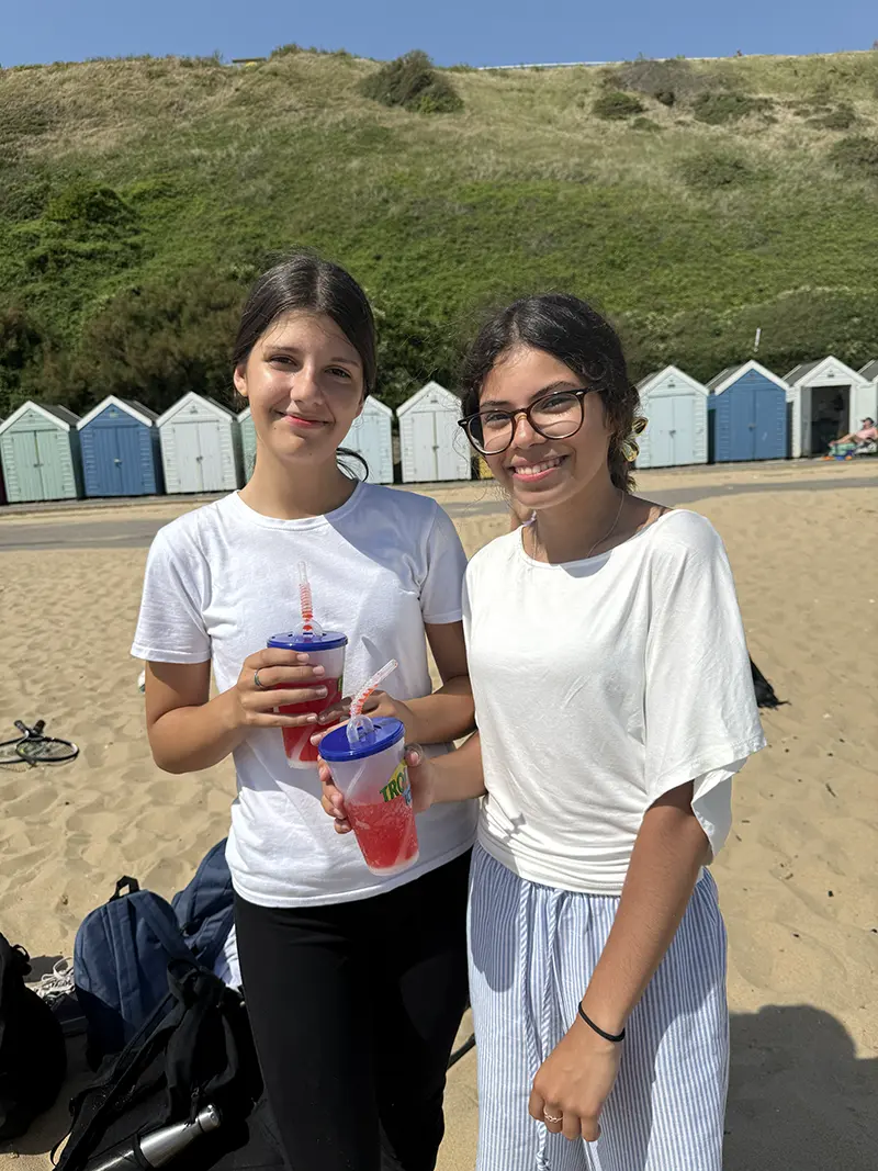 Students with drinks on beach on a school excursion